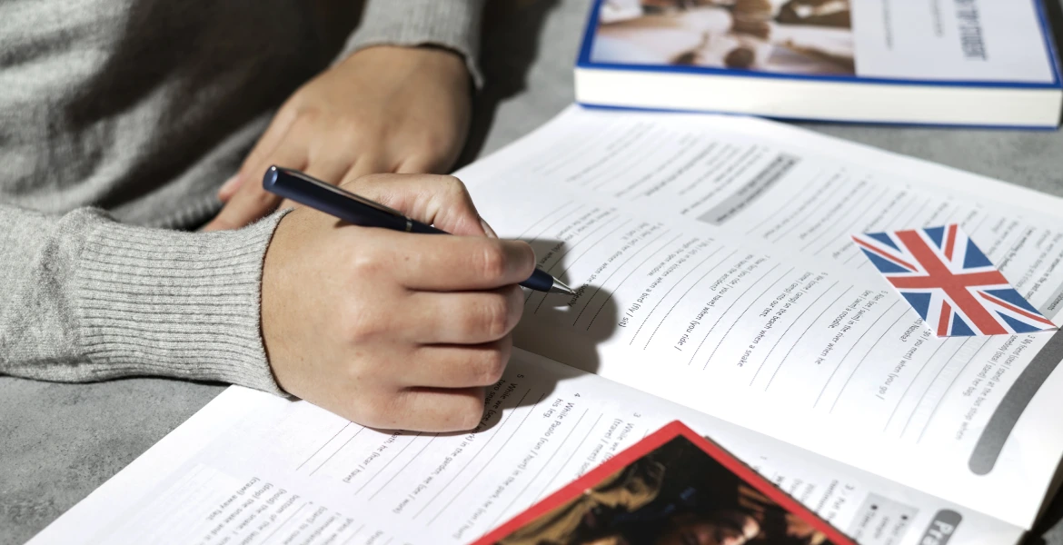 Pessoa estudando com um livro de atividades em Inglês.